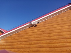 Видеокамера стоит на крыше бревенчатой постройки
